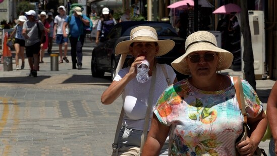 Tourists wear hats and drink water to stay cool as they walk at Ledras street in downtown Nicosia, Cyprus, Thursday. (AP)