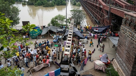 Flood hit people take shelter near a bridge as the swollen Yamuna river floods low-lying areas, in New Delhi, Thursday, (PTI)
