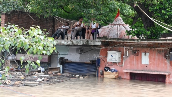 People sit above a rooftop amid the flood water at Yamuna Bazar area, in New Delhi on Thursday. (ANI)