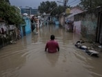 A man walks through a flooded alley at a residential colony, after water rose from the river Yamuna due to heavy monsoon rain,