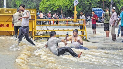 A man clicks a picture while others enjoy and bathe in floodwaters near Shantivan on Friday. (Raj K Raj/HT) A man clicks a picture while others enjoy and bathe in floodwaters near Shantivan on Friday. (Raj K Raj/HT)