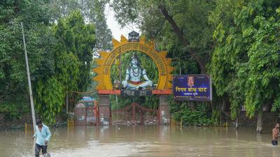 A man wades through a flooded road outside Nigam Bodh Ghat which was closed earlier this week. (PTI)