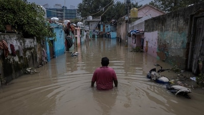 A man walks through a flooded alley at a residential colony, after water rose from the river Yamuna due to heavy monsoon rain, (REUTERS)
