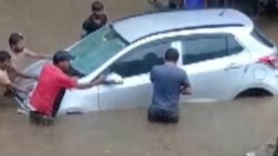 Commuters pull a car on a waterlogged road in Assam on Friday. (Twitter/ANI)