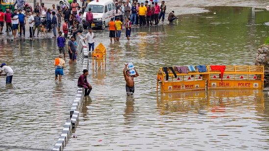 New Delhi: Locals wade through the floodwaters of the swollen Yamuna river near Hanuman Mandir at Yamuna Bazar area, Delhi on Saturday. (PTI)