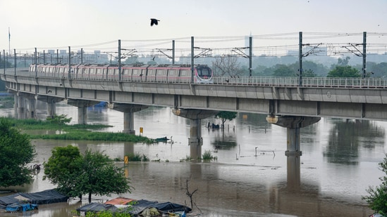 A Delhi Metro train passes by as the swollen Yamuna river floods low-lying areas, in New Delhi, Wednesday. (PTI)