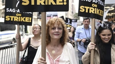 Susan Sarandon pick up a sign for the strike. Outside the Warner Bros. studios in Burbank, California, throngs of protesters chanted: “Fists up, curtains down, LA is a union town.” Food trucks flanking organizers' tents served churros, boba tea and cold lemonade to protesters baking in the midday heat that reached 98 degrees Fahrenheit (36.7 Celsius).&nbsp; 