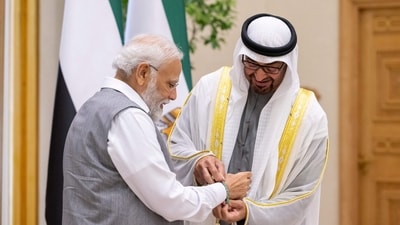 UAE President Sheikh Mohammed bin Zayed Al Nahyan ties an official COP 28 band with Prime Minister Narendra Modi at Abu Dhabi on Saturday. (AFP)