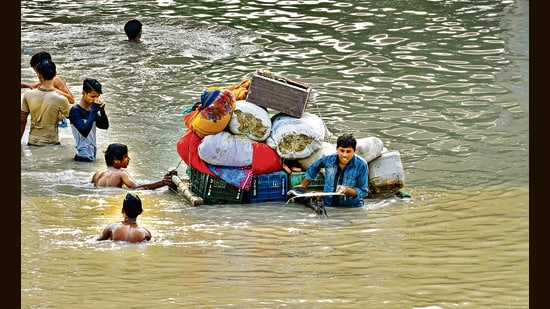 People carry their belongings at a flooded Yamuna Khadar in New Delhi on Sunday. (Sanjeev Verma/HT Photo)