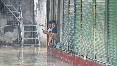 Peopel sit near shops in the flooded Tibetan Market in New Delhi on Monday. (Sanchit Khanna/HT PHOTO)