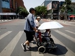 Pedestrians cross a road on a hot day amid an orange alert for heatwave, in Beijing