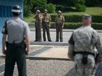 North Korean soldiers (C) take photos towards a South Korean soldier (L) and a US soldier (R) standing before the military demarcation line (lower C) separating North and South Korea within the Joint Security Area (JSA) at Panmunjom. 