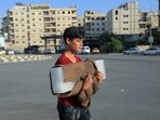 A boy carries an ice block he walks along a street during a heatwave, in Damascus, Syria