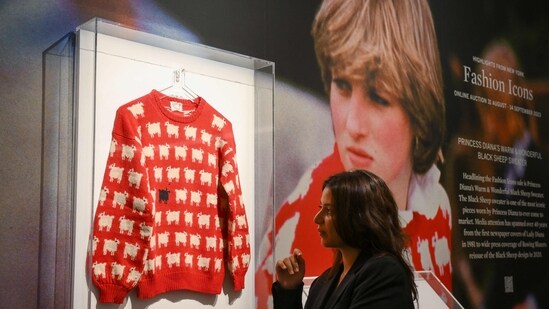 A staff member poses with the "Black Sheep Jumper" designed by Sally Muir and Joanna Osborne and worn on several occasions by Britain's late Princess Diana during a press view. (AFP)