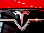 A Tesla logo on a Model S is photographed inside of a Tesla dealership.