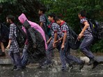 School students walk through a waterlogged road during rain, in New Delhi. School students walk through a waterlogged road during rain, in New Delhi.