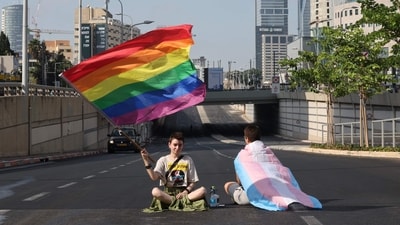 Demonstrators lift Pride and Transgender flags as they sit on a road during a 'day of resistance' to protest the Israeli government's judicial overhaul bill, in Tel Aviv on July 18, 2023. The proposals have divided the nation and triggered one of the biggest protest movements in Israel's history since being unveiled in January by the hard-right government of Prime Minister Benjamin Netanyahu. (Photo by JACK GUEZ / AFP) (AFP)