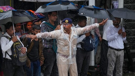 A traffic police personnel manages traffic during monsoon rains, in Mumbai, Wednesday. A traffic police personnel manages traffic during monsoon rains, in Mumbai, Wednesday.