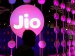 A man walks across the LED board showing the logo of Jio