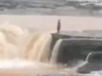 In the clip, the woman is seen standing on the edge of the waterfall before taking the leap. (Screengrab/Twitter)
