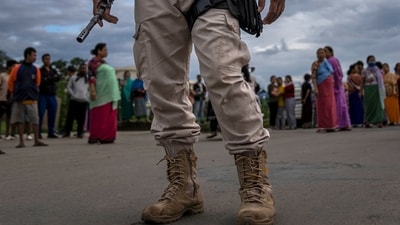 A Manipur policeman stands guard as members of Meira Paibis, powerful vigilante group of Hindu majority Meitei women, block traffic to check vehicles for members from rival tribal Kuki community, in Imphal, (AP) A Manipur policeman stands guard as members of Meira Paibis, powerful vigilante group of Hindu majority Meitei women, block traffic to check vehicles for members from rival tribal Kuki community, in Imphal, (AP)