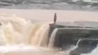 In the clip, the woman is seen standing on the edge of the waterfall before taking the leap. (Screengrab/Twitter) In the clip, the woman is seen standing on the edge of the waterfall before taking the leap. (Screengrab/Twitter)