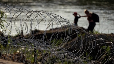 Migrants walk along concertina wire as they try to cross the Rio Grande at the Texas-U.S. border in Eagle Pass, Texas, Thursday, July 6, 2023. (AP Photo/Eric Gay) (AP) Migrants walk along concertina wire as they try to cross the Rio Grande at the Texas-U.S. border in Eagle Pass, Texas, Thursday, July 6, 2023. (AP Photo/Eric Gay) (AP)