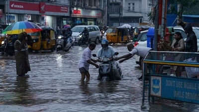 A traffic police officer, right and a man, left help a motorist at a water logged street during rain in Hyderabad, India, Thursday. (AP) A traffic police officer, right and a man, left help a motorist at a water logged street during rain in Hyderabad, India, Thursday. (AP)