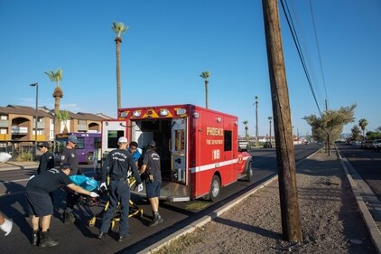 Firefighters and paramedics from Phoenix Fire Station 18 wheel a resident to an ambulance from a bus stop during a heat wave in Phoenix, Arizona, (Bloomberg)