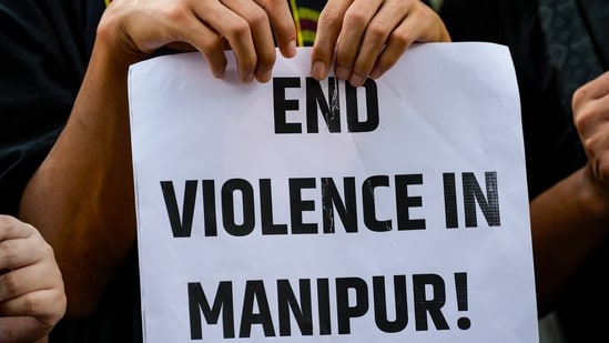 A protester holds a placard during a protest against the ongoing ethnic violence in Manipur state, in New Delhi on Friday. (PTI)