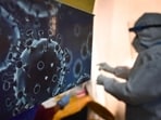An illustration of the novel coronavirus seen next to a health care worker at a Covid-19 testing centre in New Delhi.