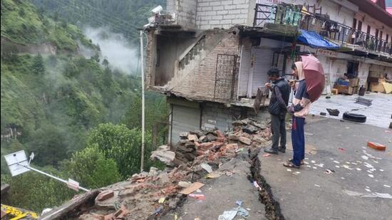 A building collapses while the others remain at risk after cracks emerge on the road at Khaltu Nalah market following heavy rain in Kotkhai of Shimla on Saturday. (HT Photo)
