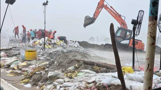 Workers plugging a breach at dhussi bundh amid heavy rainfall in Jalandhar on Saturday. (HT Photo)