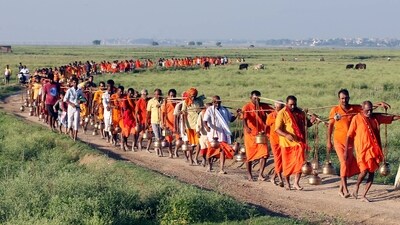 Kanwariyas (Shiva devotees) carrying metal pots filled with water from the Ganges River during their annual Kanwar Yatra, in Prayagraj on Sunday. (ANI)