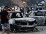 People inspect burnt vehicles after raging wildfires in Bouira, 100 km from Algiers, Algeria, Monday. 