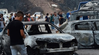 People inspect burnt vehicles after raging wildfires in Bouira, 100 km from Algiers, Algeria, Monday. (AP) People inspect burnt vehicles after raging wildfires in Bouira, 100 km from Algiers, Algeria, Monday. (AP)