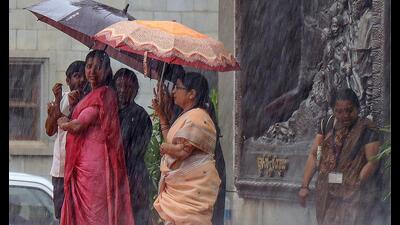 Commuters take shelter under umbrellas during heavy monsoon rain, in Bengaluru. (PTI) Commuters take shelter under umbrellas during heavy monsoon rain, in Bengaluru. (PTI)