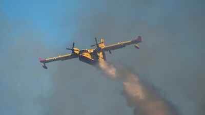 A Canadair aircraft drops water over a wildfire in Vati village, on the Aegean Sea island of Rhodes, southeastern Greece, on Tuesday. (AP) A Canadair aircraft drops water over a wildfire in Vati village, on the Aegean Sea island of Rhodes, southeastern Greece, on Tuesday. (AP)