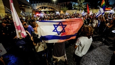 A protester holds a flag stained, with what he claims is blood, during a demonstration, following a parliament vote on a contested bill that limits Supreme Court powers to void some government decisions, near the Knesset, Israel's parliament in Jerusalem on Monday. (Reuters)