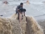 The two local teenagers held onto a railing as the river was overflowed due to incessant heavy rainfall. (Twitter/ANI)