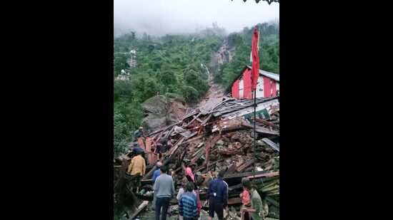 People gather near a building destroyed by flash floods and heavy rain in Kandhar village of Rampur in Shimla on Wednesday. (ANI)