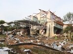 People speak on their phones in front of a house damaged by an explosion at a firework warehouse in Narathiwat province southern Thailand.