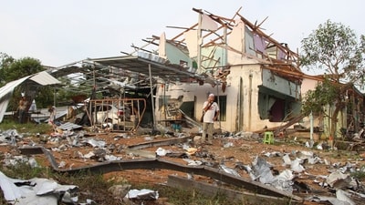 People speak on their phones in front of a house damaged by an explosion at a firework warehouse in Narathiwat province southern Thailand. (AP)