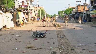 A damaged two-wheeler lies on the road as Police personnel deployed after a clash erupted between two groups in Haryana's Nuh on Monday. (ANI) A damaged two-wheeler lies on the road as Police personnel deployed after a clash erupted between two groups in Haryana's Nuh on Monday. (ANI)