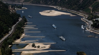 Transport vessels cruise past the partially dried riverbed of the Rhine river in Bingen, Germany. (REUTERS)