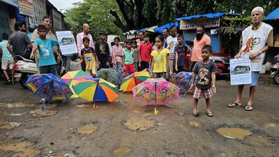 Mumbai, India - July 29, 2023 : The Members of Watchdog foundation with Childrens did a Unique Protest by covering the potholes by Colourful umbrellas near Our Lady of Velankanni Grotto, Sahar Village at Andheri, in Mumbai, India, Saturday, July 29, 2023. (Photo by Vijay Bate/HT Photo)