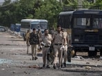 Broken glass and debris strewn on a street as policemen patrol after communal clashes in Nuh, on Tuesday. (AP)