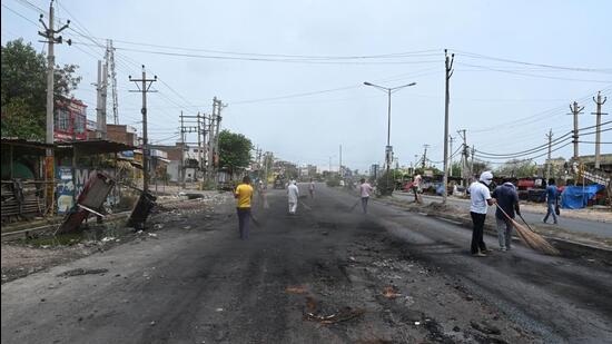 Workers remove the debris and stone from the road after the communal violence in Nuh. (Parveen Kumar/HT PHOTO)
