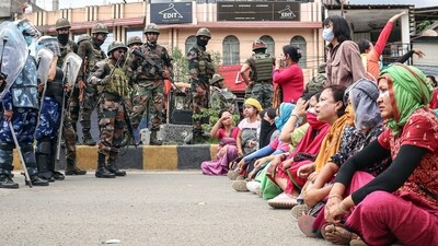 Paramilitary personnel stand guard as people stage a protest against the mass burial of Kuki-Zomi people killed in Manipur's ethnic violence, in Imphal on Thursday. (ANI Photo) Paramilitary personnel stand guard as people stage a protest against the mass burial of Kuki-Zomi people killed in Manipur's ethnic violence, in Imphal on Thursday. (ANI Photo)