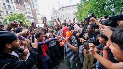 The crowd eggs on a person holding a toy gun wearing a spider man mask, Friday, in New York's Union Square. (AP)